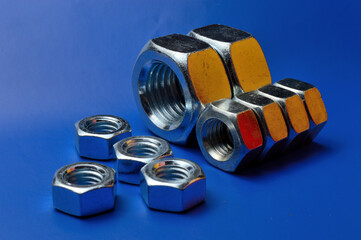 chrome plated, metal nuts of different sizes, highlighted in different colors, laid out on a blue background.