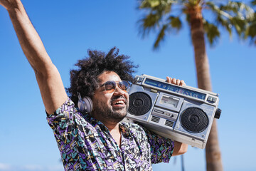 Young latin man dancing while listening music from vintage boombox stereo