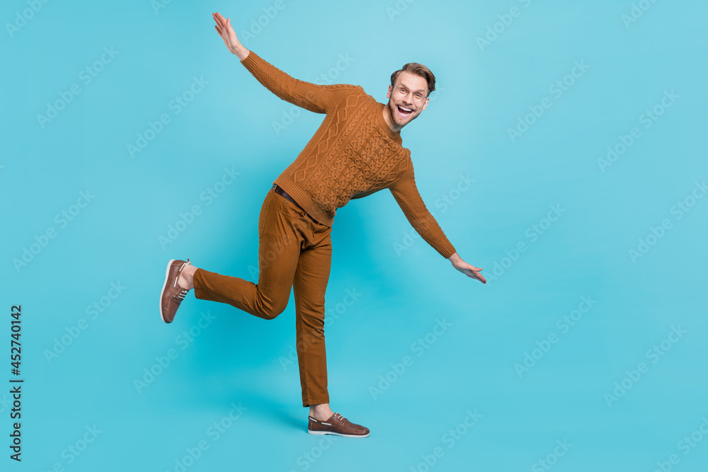 Poster full body photo of charming happy young man dance hands wings smile isolated on blue color backgroun