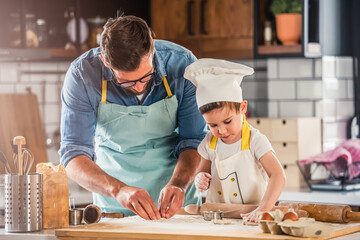 Family together in the kitchen. Father making cake with his toddler son.