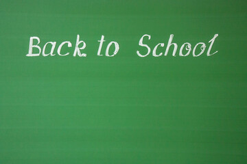 Obraz premium English lettering - back to school written in white chalk on a green chalkboard and copy space. Concept - offline education
