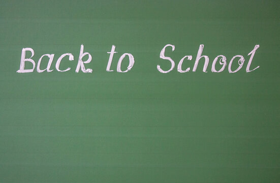 Naklejki Handwritten inscription: back to school and copy space on a green chalkboard with chalk streaks