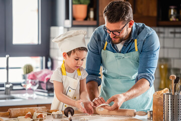 Family together in the kitchen. Father making cake with his toddler son.