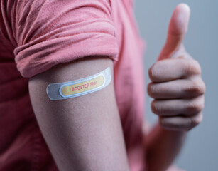 covid-19 or coronavirus vaccinated shoulder with booster shot sticker and thumbs up gesture - concept of approved coronavirus 3rd dose vaccination for immunocompromised. - obrazy, fototapety, plakaty