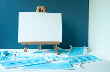 wooden easel with white board with space for text, blue medical masks
