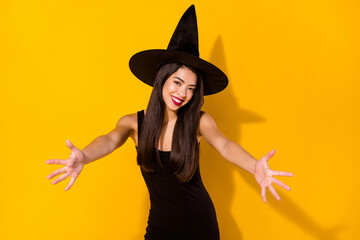 Photo of sweet young brunette hairdo lady hug you wear black dress witch cap isolated on yellow...