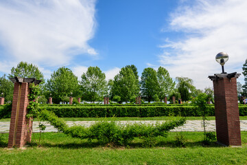 Landscape with grass, roses and large old green trees towards clear blue sky in King Michael I Park (Herastrau), in a sunny spring day in Bucharest, Romania.