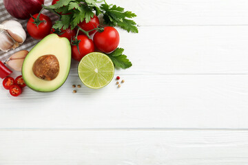 Fresh guacamole ingredients on white wooden table, flat lay. Space for text