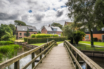 Fototapeta na wymiar Wooden bridge over a small water canal in a beautiful park in the oldest city of Denmark, Ribe