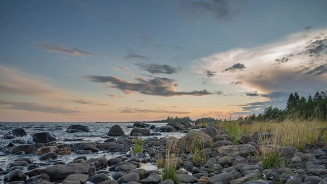 4K time lapse of Magnificent Soft and colorful sunset by the seaside stone. Beautiful cloud movement with seashore stones. Gradual light reduction.
