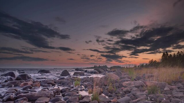 4K time lapse of Magnificent Soft and colorful sunset by the seaside stone. Beautiful cloud movement with seashore stones. Gradual light reduction.