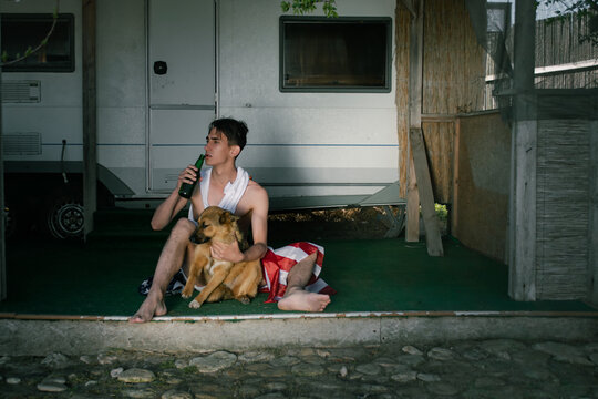A caring man sits on the porch with his dog. Traveling with a pet.