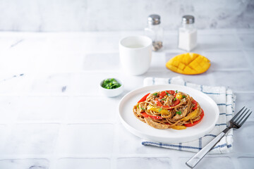Buckwheat pasta with chicken, mango and red pepper in a plate