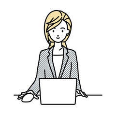 デスクで座ってPCを使っているスーツの女性