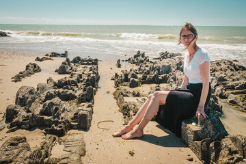 Pretty woman enjoying sun on the rocky beach