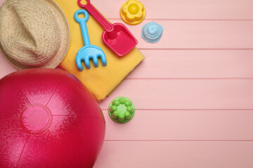 Flat lay composition with beach ball and sand toys on pink wooden background. Space for text