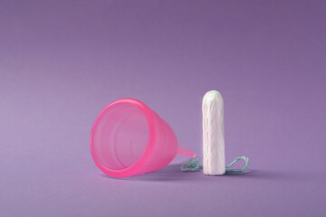 Menstrual cup and tampon on violet background