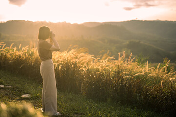 solo woman travel take photo and sightseeing sunrise on mountain at thailand