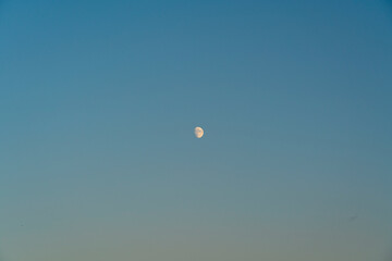 The moon in a blue-orange cloudless sky, mood at sunset, concept of vacation and wanderlust 