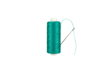 The needle is stuck in a spool of green thread. The thread passes through the eye of the needle.