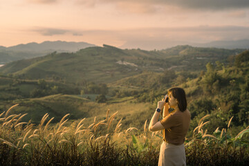 solo woman travel take photo and sightseeing sunrise on mountain at thailand