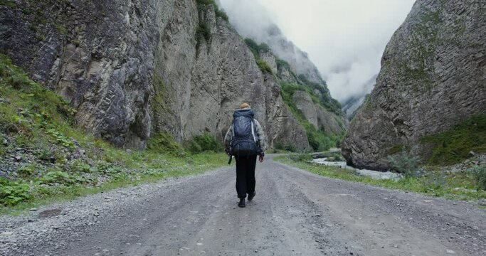 Russia, Caucasus, Elbrus. A tourist walks along a wide road among rocks
