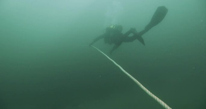 Scuba Diver Swimming Along Anchor Line In Heavy Current Low Visibility.