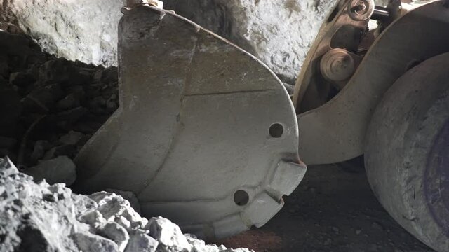 Underground loader picks up ore mass with bucket