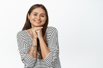 Fototapeta premium Beauty and skin care. Tender young woman showing her clean, healthy face, smiling and looking happy at camera, white background