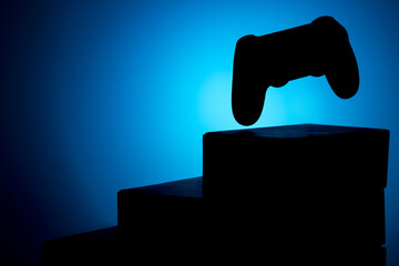 the silhouette of the gamepad above the pedestal of boxes, the background is blue © metelevan