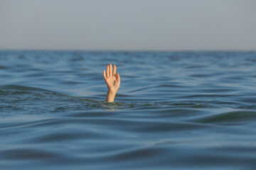 Drowning woman reaching for help in sea