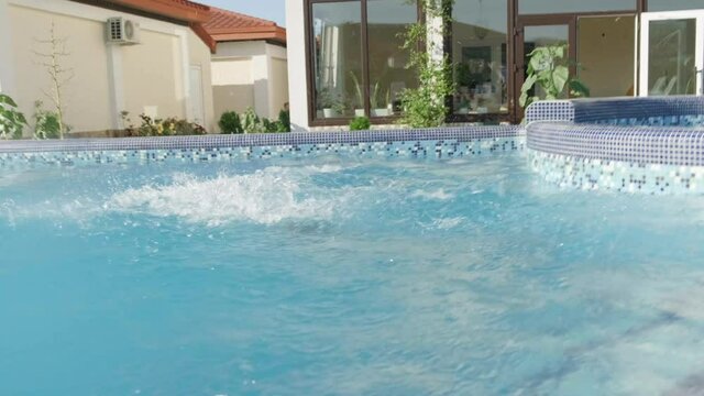  happy little boy running and jumping in swimming pool, child having fun, splashing water. Summer travel family hotel vacation tourists