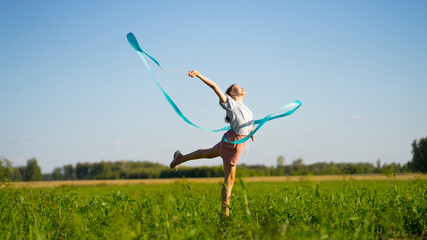 Girl in the field with a blue gymnastic ribbon