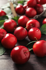 Delicious ripe cherry plums with leaves on wooden table, closeup