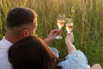 Picnic in the field. Young couple in love drinking wine outdoors.