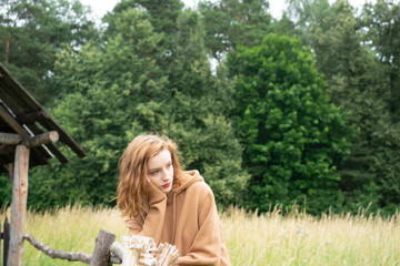 Obraz premium young beautiful woman posing in the summer in a field in a brown sweater