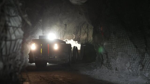 The underground loader moves in reverse and lifts the bucket