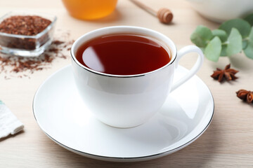 Freshly brewed rooibos tea, dry leaves and anise on white wooden table