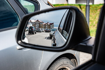 Parking lot reflecting in side rear-view mirror on car.