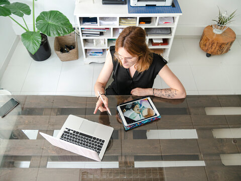 Woman With Graphic Tablet And Laptop In Creative Workspace