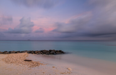 Long exposure water of Indian ocean with stones on the Maldivian island. Sunset time. Crossroads Maldives, july 2021