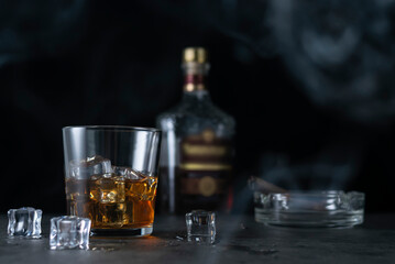 Whiskey on the rocks in a clear glass. An ashtray with a cigarette