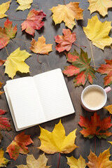 Naklejka na ściany i meble Autumn mood flat lay. Cup of coffee, notebook, autumn leaves on dark wooden background. Autumn stylish mockup with blank notebook, top view, copy space.