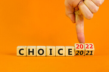 Planning 2022 choice new year symbol. Businessman turns wooden cubes and changes words 'choice 2021' to 'choice 2022'. Beautiful orange background, copy space. Business, 2022 choice new year concept.