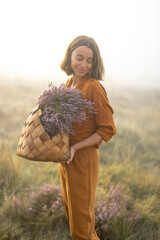 Portrait of a cute woman with a freshly picked up heather bouquet in the mountains in a foggy...
