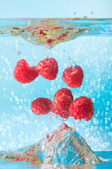 Raspberry with water splash against light blue background