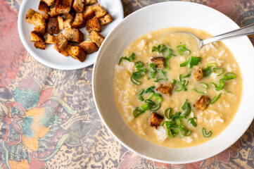 Creamy vegetable soup with rice and green onion shoot, roasted sliced bread.