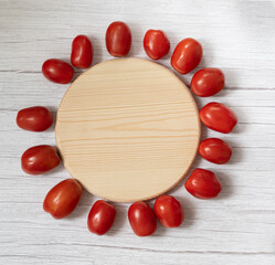 Naklejka na ściany i meble Tomatoes with a wooden round board on a light background