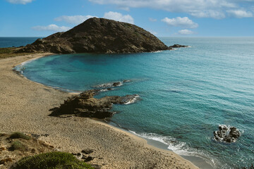 View of beautiful pristine Sa Mesquida beach in Menorca island in Spain, empty, with clean turquoise water and blue sky on a summer day