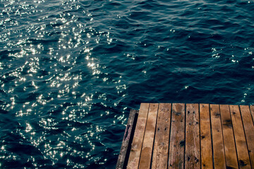 Wooden pier at the blue water of the sea in sunlight